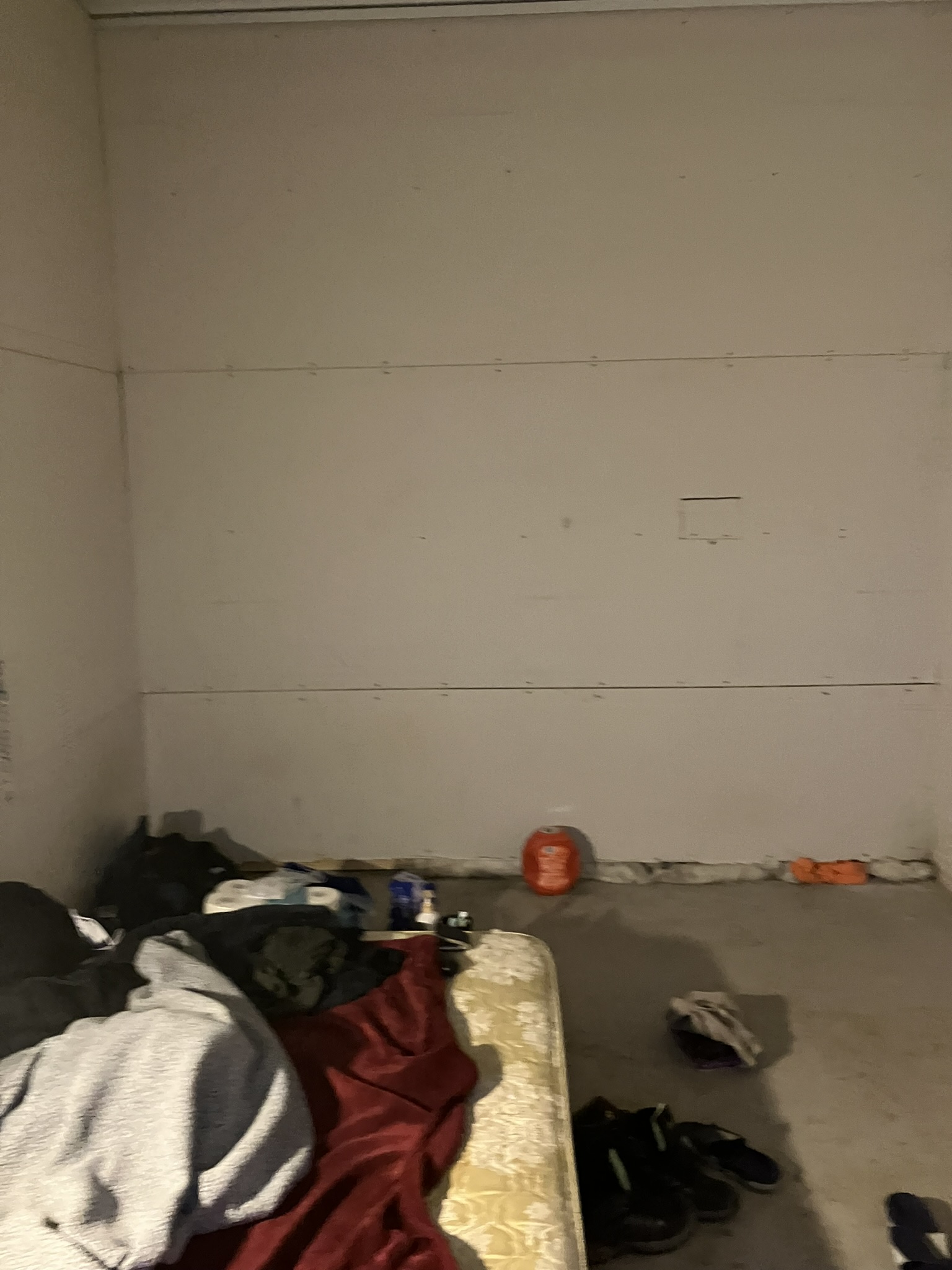 photo of bedroom with exposed drywall and bed on the floor