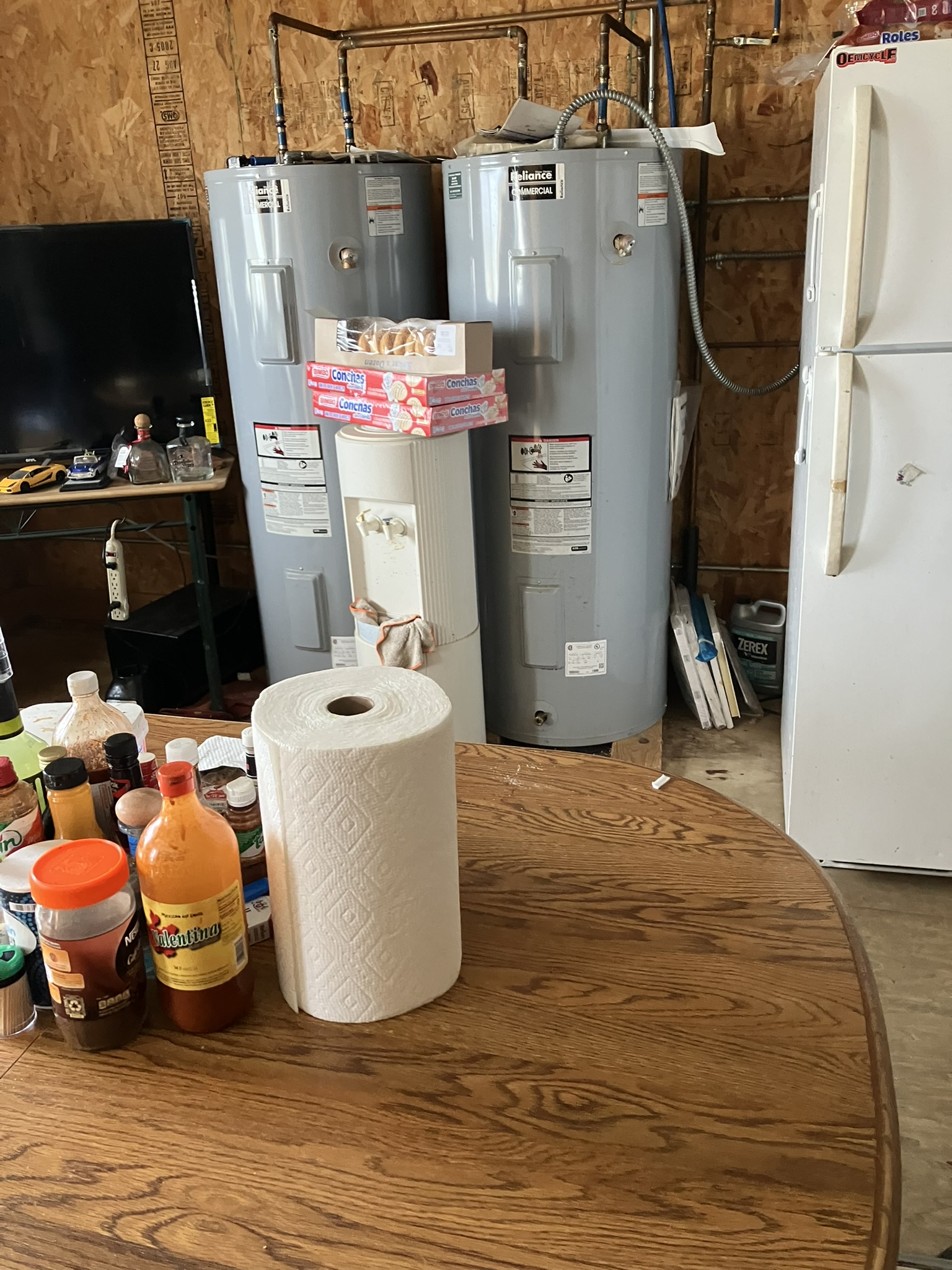 photo of kitchen with exposed pipes, water heater, and plywood wall