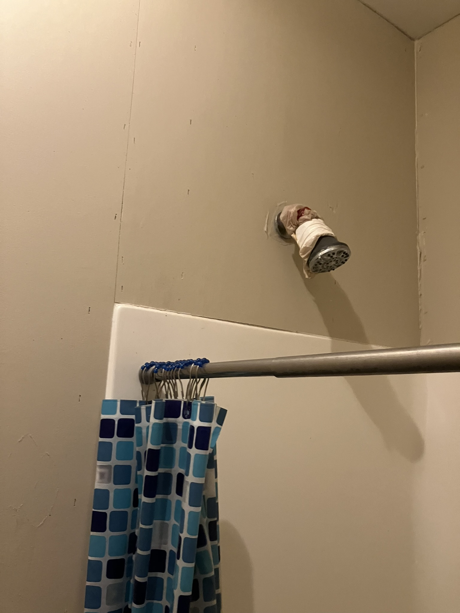 photo of a shower head with exposed drywall